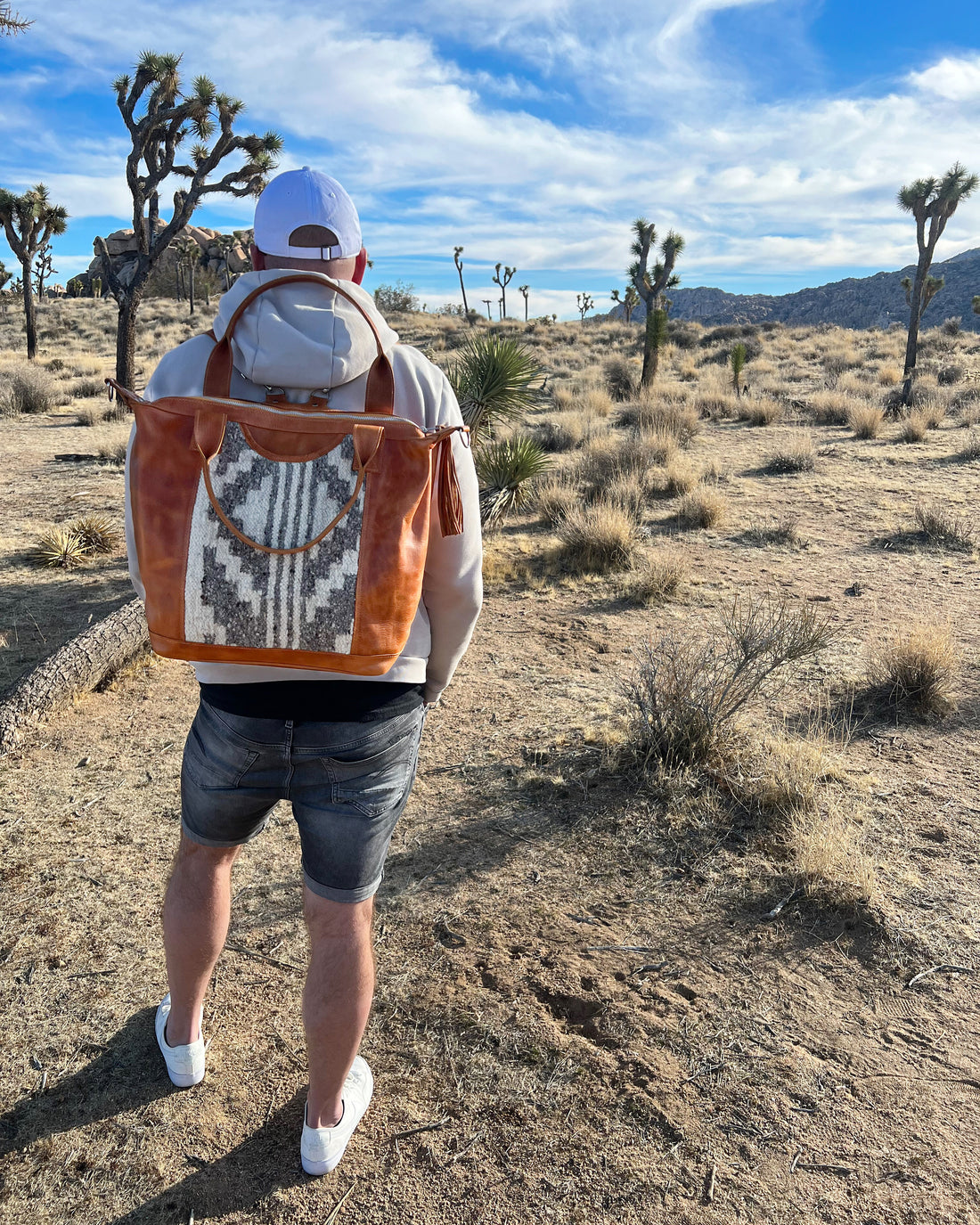 Man standing in dessert with convertible leather bag. 